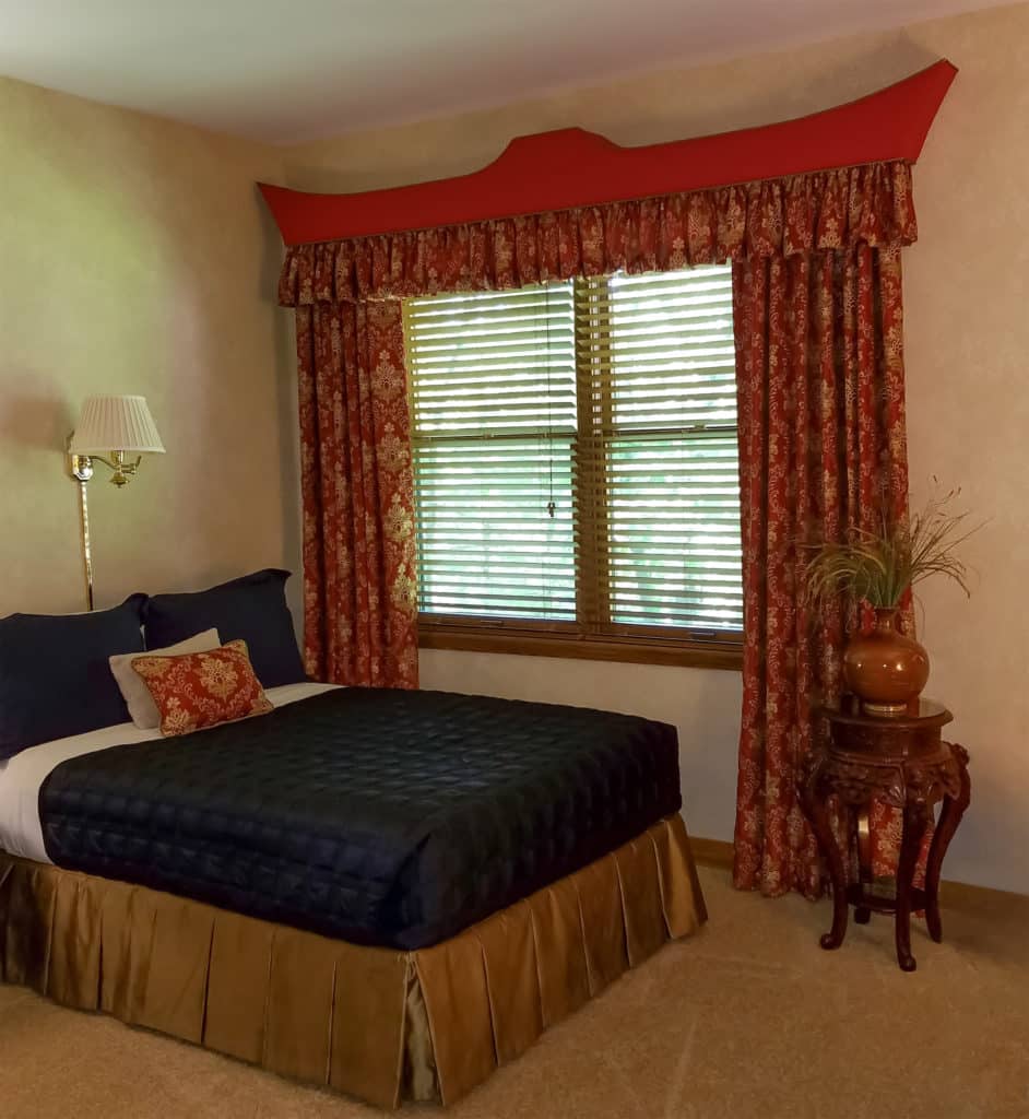 Custom odd-shaped cornice with red fabric and ornate red and gold curtains